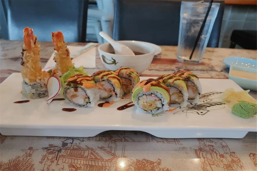 Sushi assortment with tempura shrimp, rolls, and garnishes on a plate.