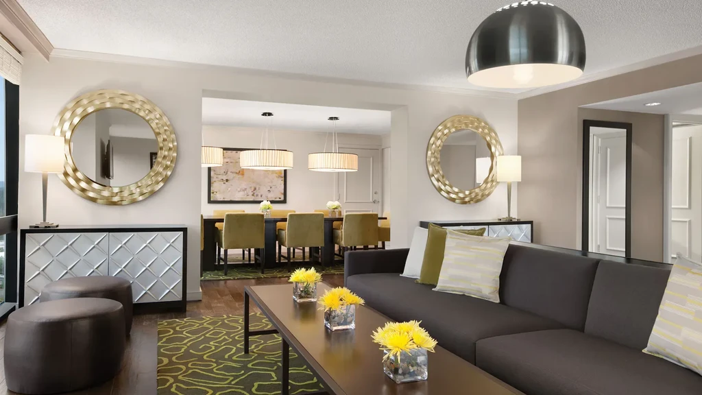 Contemporary living room with grey sofa, yellow flowers, and olive green dining chairs.
