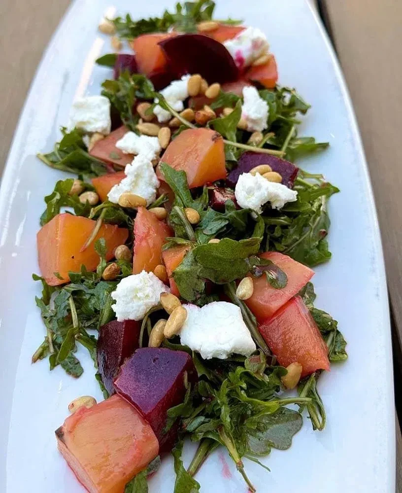 Salad with dark greens, beets, white cheese, and pine nuts.