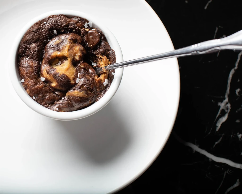 Warm chocolate chip dessert with sea salt and spoon in ramekin.