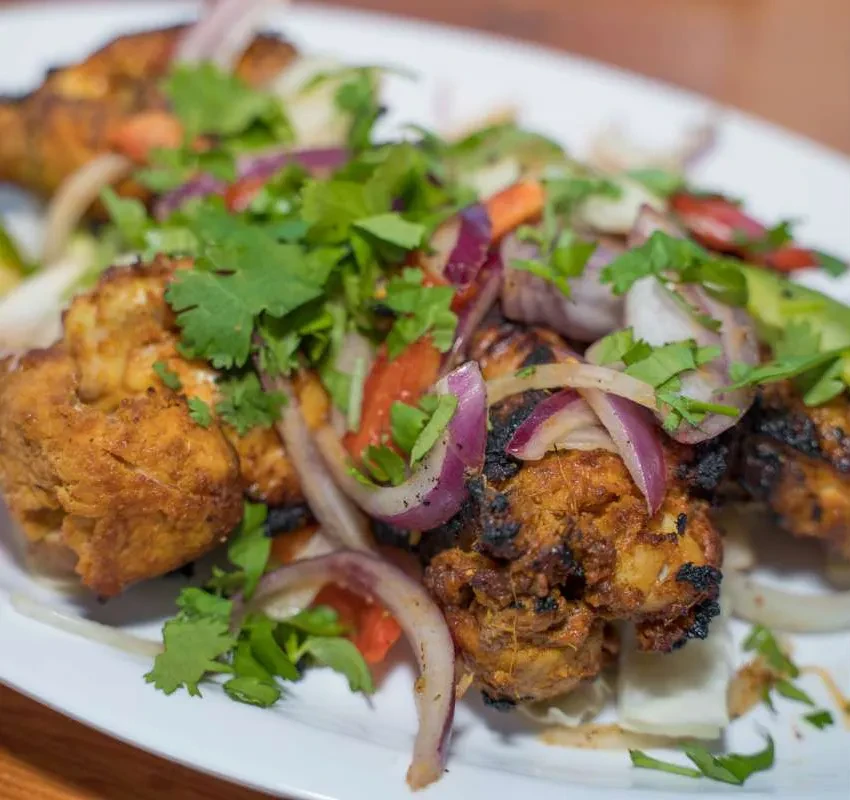 Roasted chicken pieces with red onion, cilantro, and tomato.