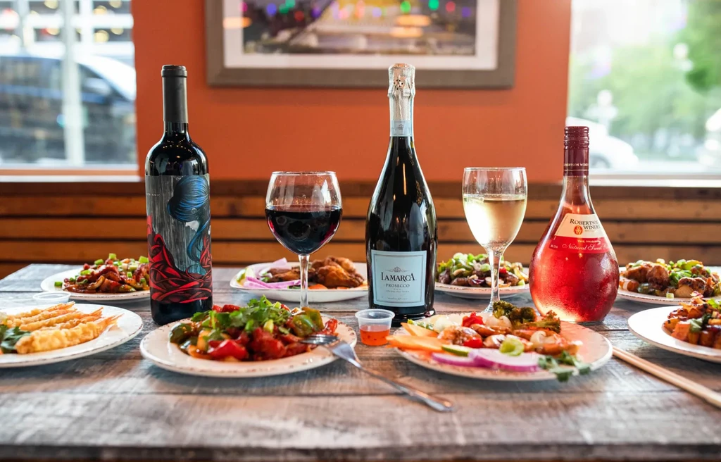 Restaurant dining table with diverse food, Prosecco, rosé, and red wine.