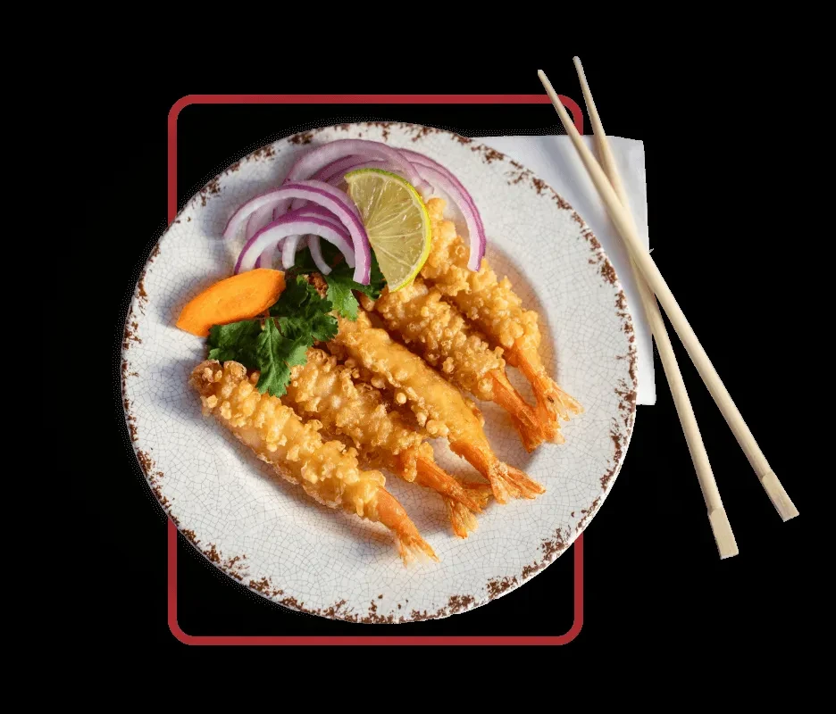Five fried shrimp with garnishes, lime, and chopsticks on a black background.