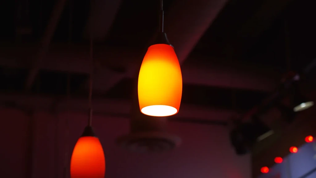 Two orange-yellow and reddish-orange pendant lights glow in a dark room.