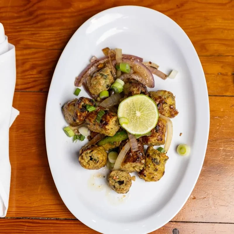 Oval plate of browned kofta garnished with onions and a lime slice.