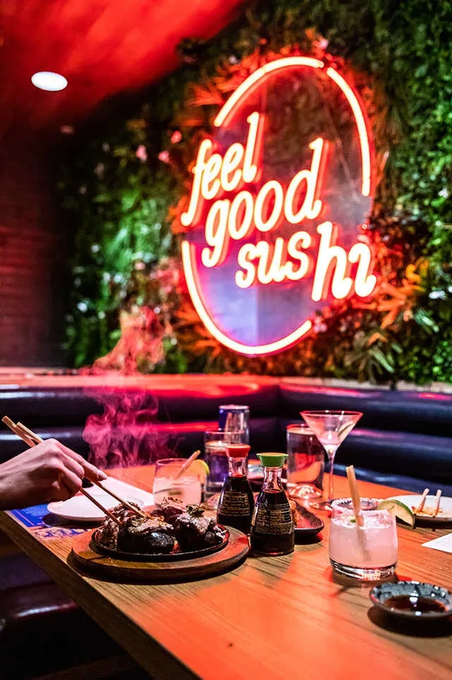Sizzling food and drinks on a dimly lit restaurant table, neon sign.