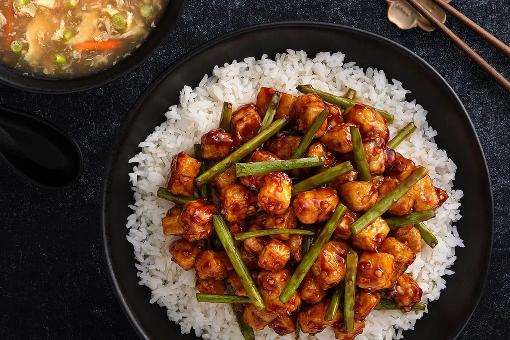 Overhead of Asian glazed chicken, rice, green beans, and soup.