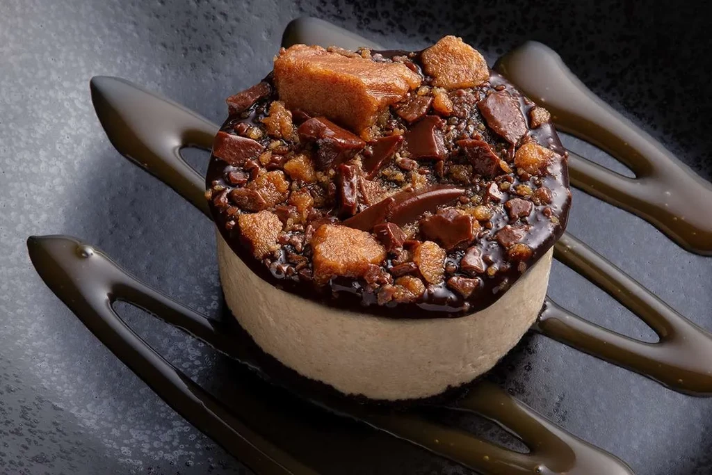 Glossy chocolate ganache dessert with caramel and sauce drizzles.