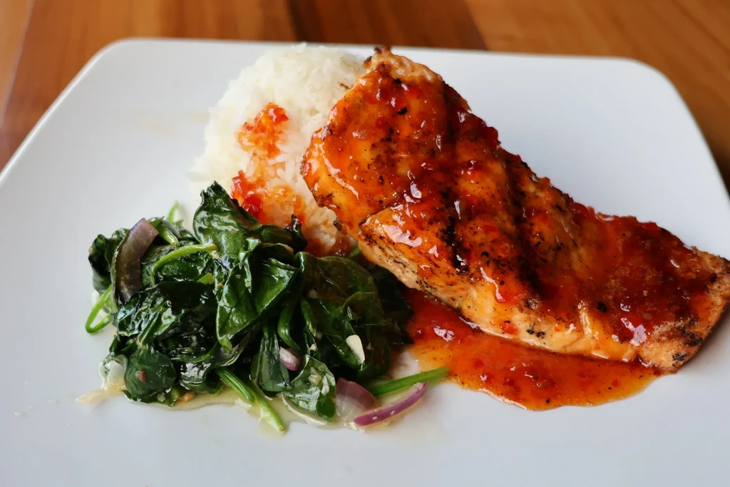 Grilled salmon with glistening orange sauce, rice, and green vegetables.
