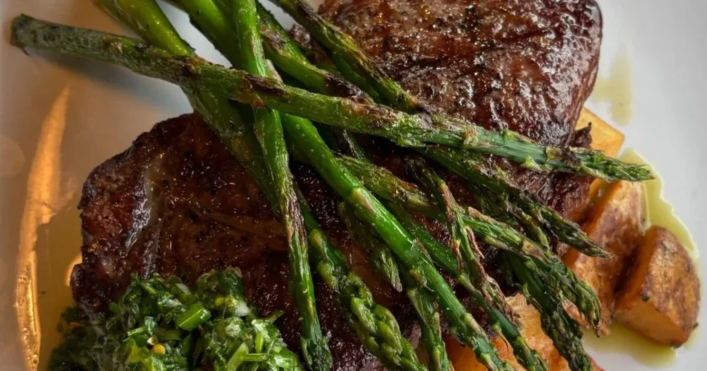 Grilled steak with asparagus, green sauce, and roasted potatoes.