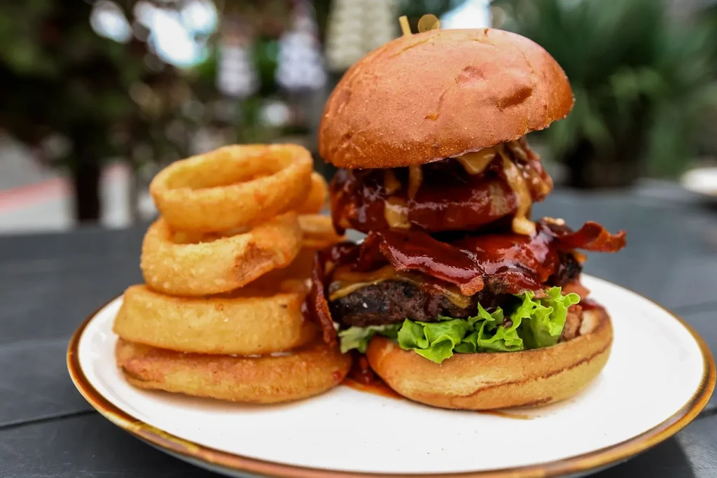 Gourmet double burger with bacon, cheese, and onion rings.