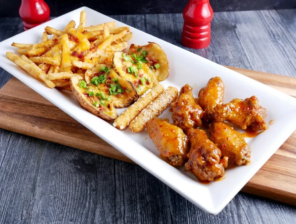 White platter with fries, potato skins, fried items, and chicken wings.