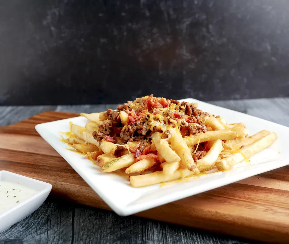 Loaded fries topped with ground meat, melted cheese, and dipping sauce.