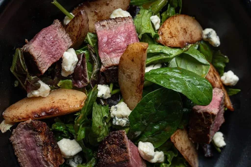 Steak salad with mixed greens, white cheese, and seared pear.