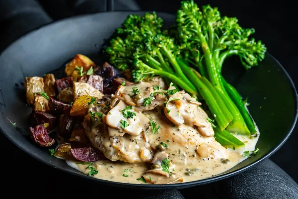 Chicken with creamy mushroom sauce, roasted potatoes, and broccolini.