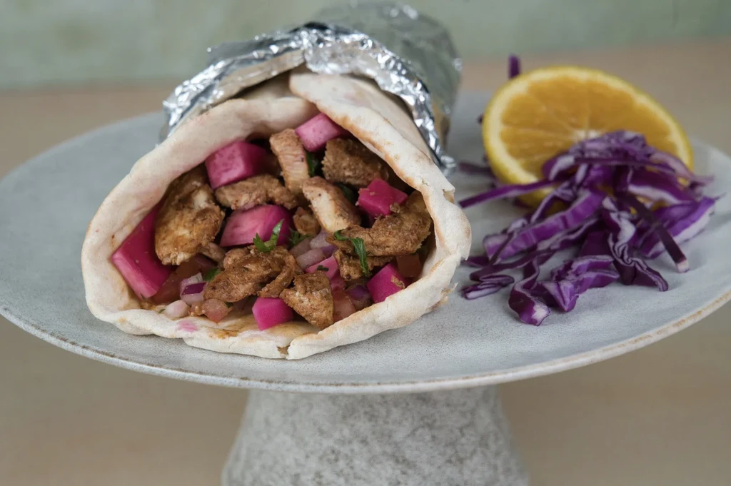 Chicken shawarma wrap with pickled vegetables, lemon, and cabbage.