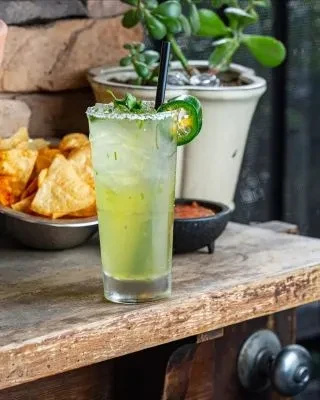Light green cocktail, salted rim, jalapeño, tortilla chips, and salsa.