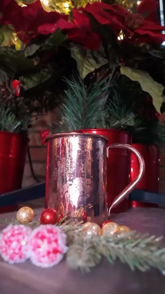 Hammered copper mug with condensation amid festive holiday decor.