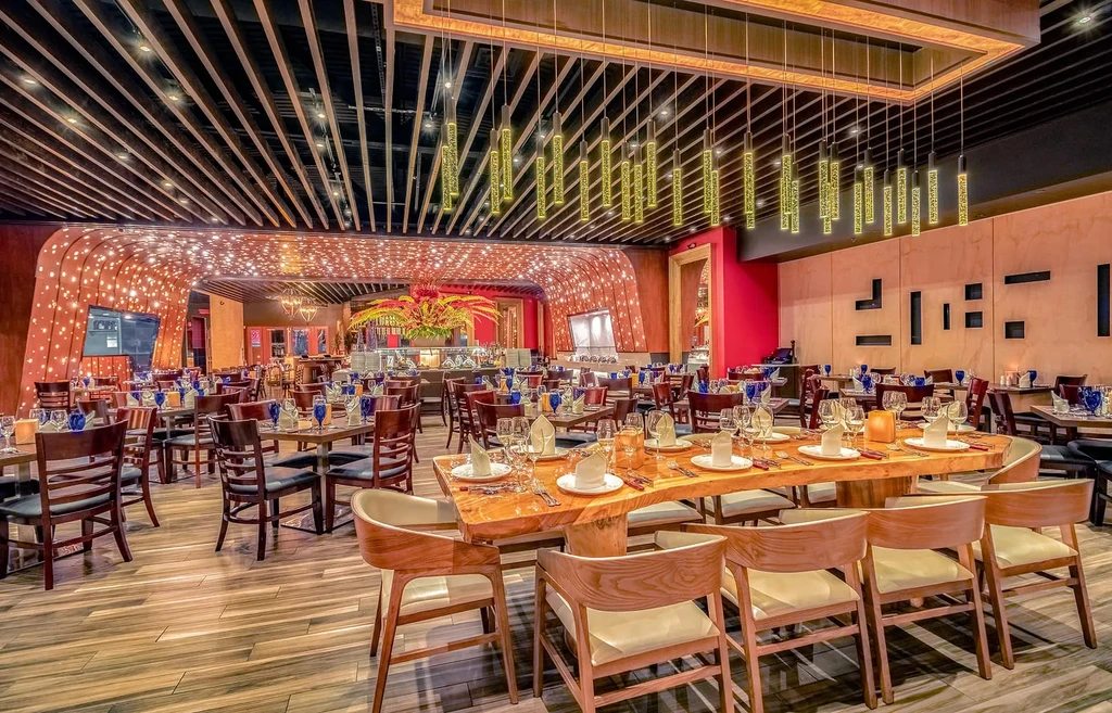 Expansive, modern restaurant dining room with a long communal wooden table.