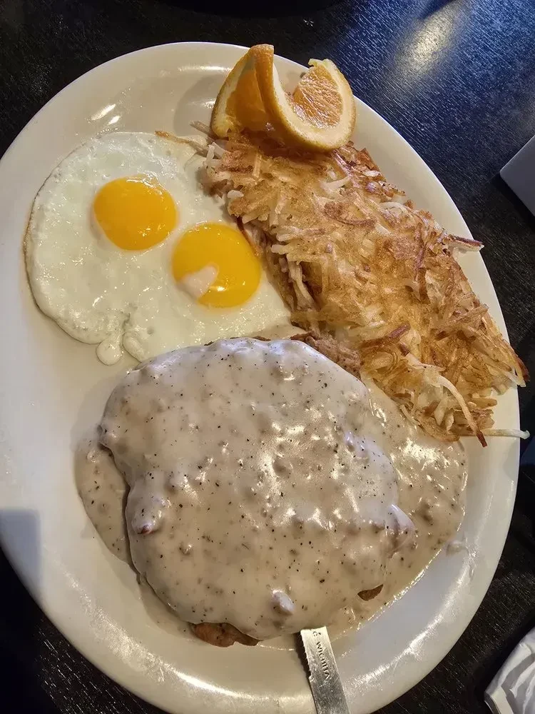 Sunny-side-up eggs, hash browns, and gravy-covered country-fried steak.
