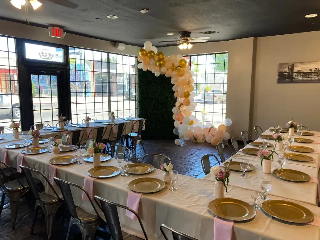 Event space with U-shaped tables, balloon arch, and floral centerpieces.