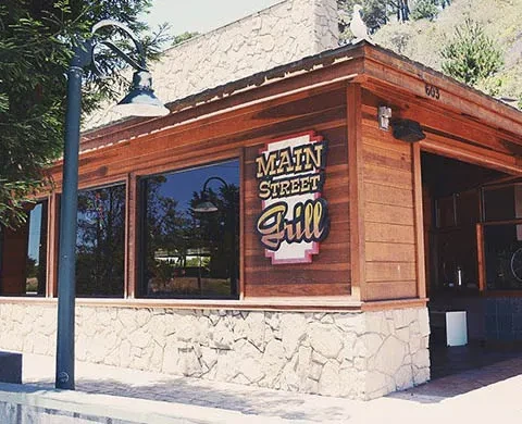 Rustic Main Street Grill building, stone base, wood upper, reflective windows.