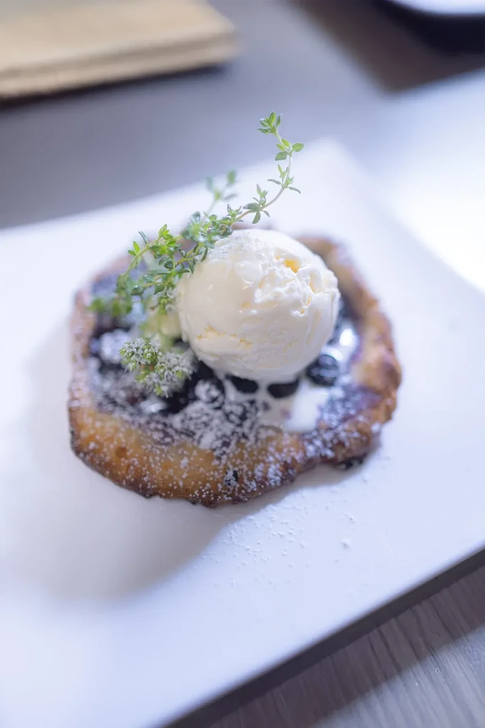 Rustic berry tart with melting vanilla ice cream, powdered sugar, and herb.