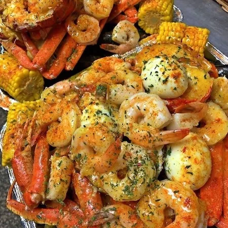 Close-up of seasoned seafood boil with shrimp, crab, corn, and eggs.