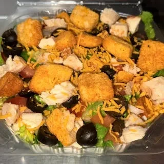 Chicken salad with lettuce, cheese, and tomatoes in a plastic takeout container.