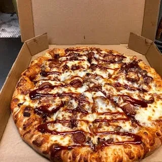 Sliced barbecue meat pizza with cheese in an open box.