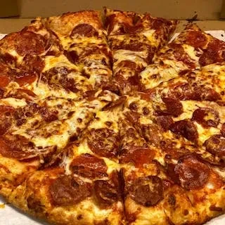Close-up of a sliced pizza with pepperoni, sausage, and melted cheese.