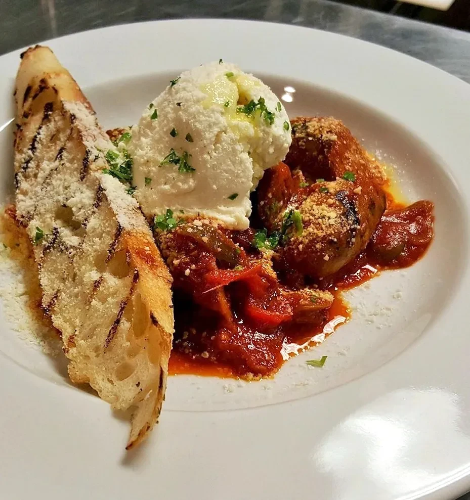 Meatballs in red sauce with ricotta, herbs, and grilled cheesy bread.