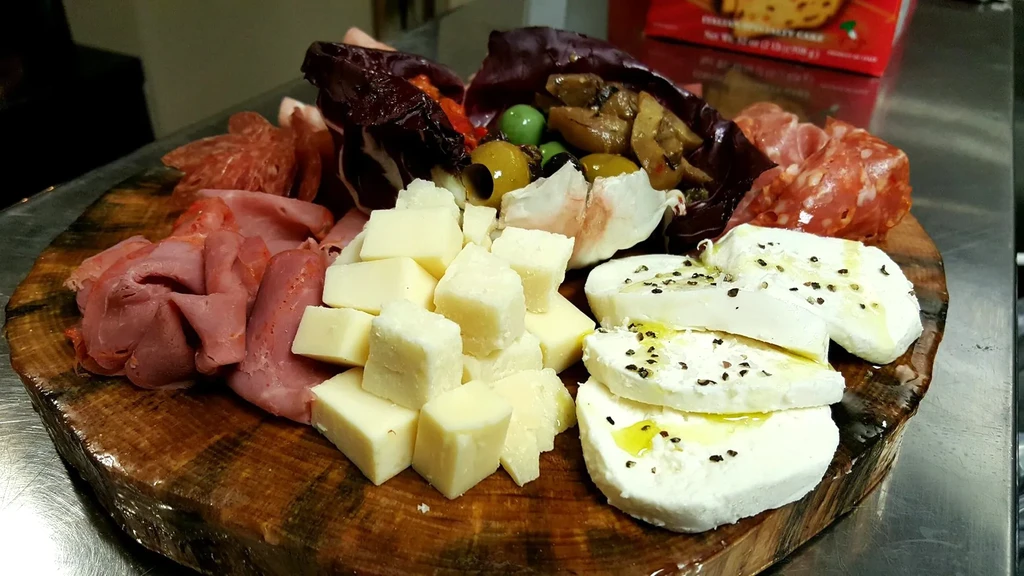 A rustic wooden charcuterie board with cheeses, cured meats, and vegetables.