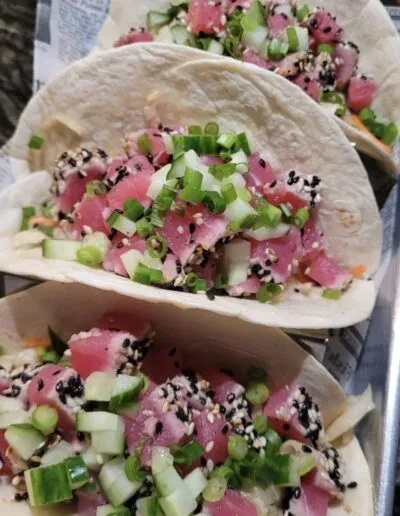 Three tuna poke wraps with cucumber, green onion, sesame seeds.