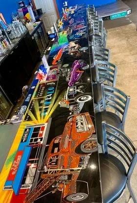 Bar counter with colorful embedded artwork of classic cars and street scenes.