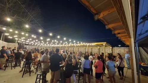 Outdoor patio at night, bustling with people under glowing fairy lights.