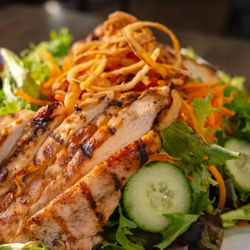 Grilled chicken salad with mixed greens, fried onions, and cucumber.