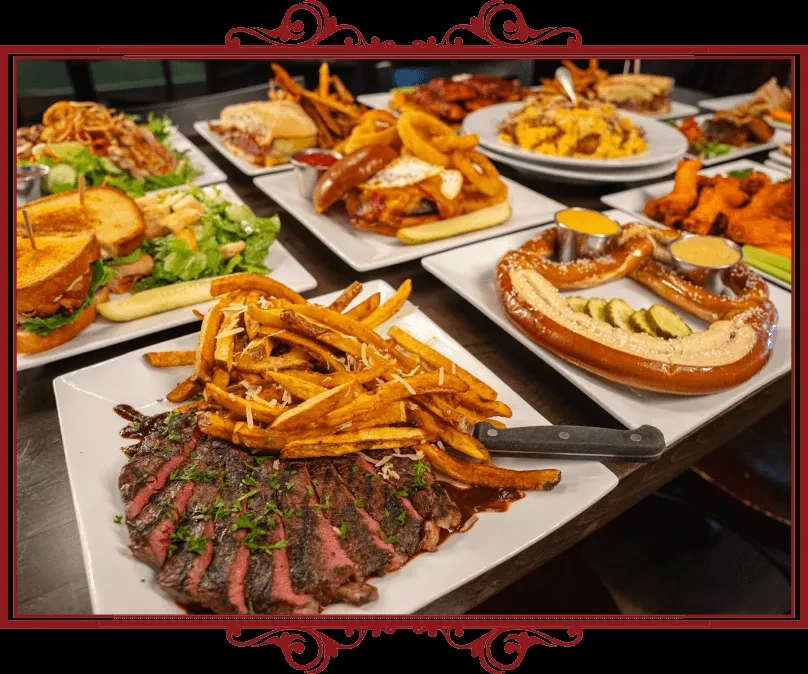 Varied food spread on table: steak, fries, pretzel, burgers, chicken wings.