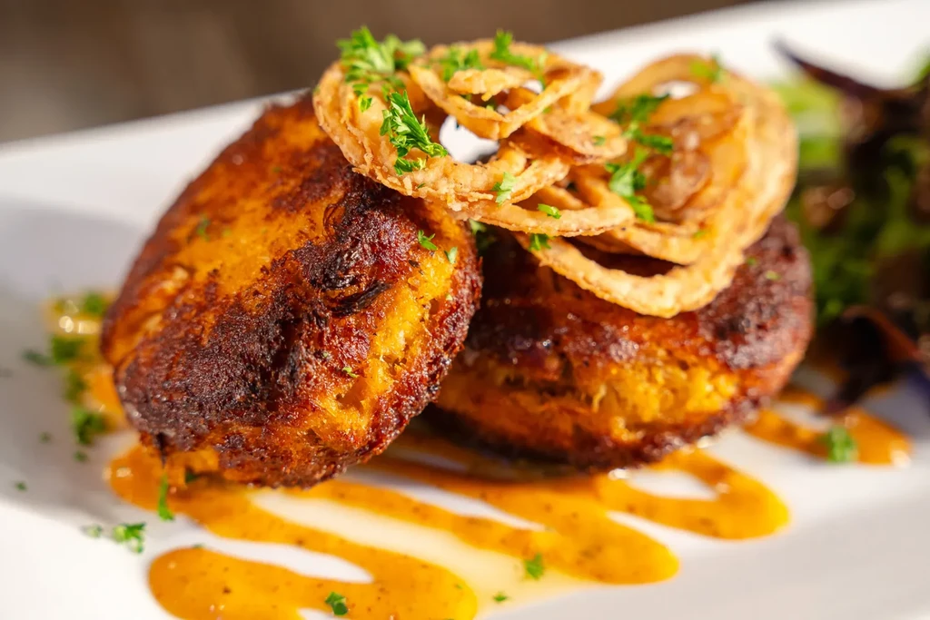 Golden-brown crispy patties, onion rings, parsley, and orange sauce.