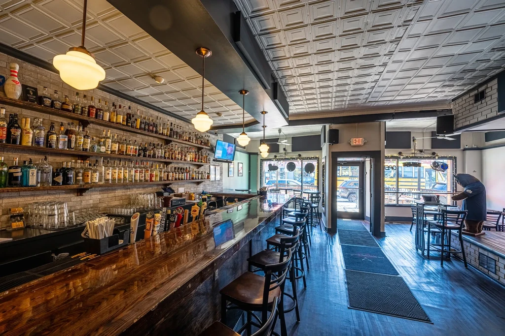 Modern bar interior with bear mascot, laptop, and street view.