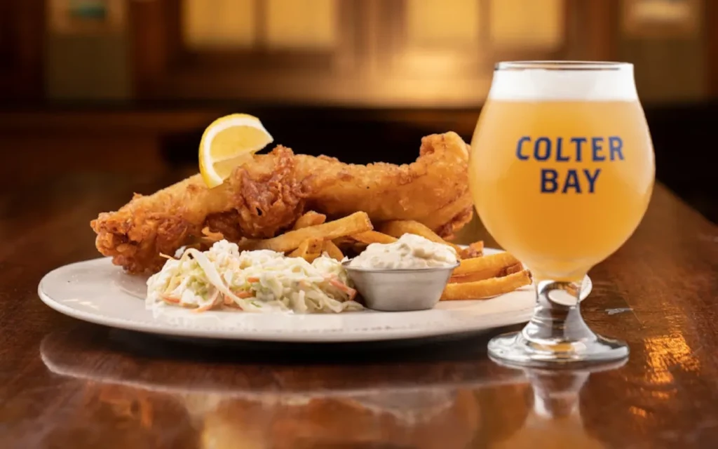 Golden fish and chips, coleslaw, tartar sauce, lemon, and a beer.