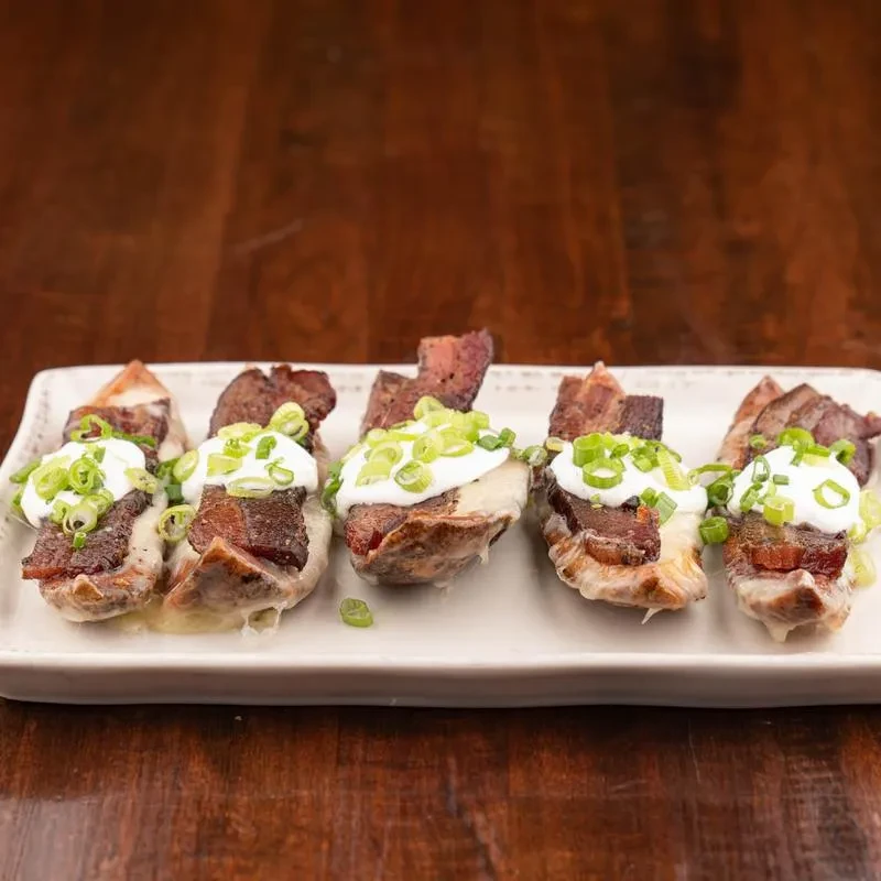 Six loaded potato skins topped with cheese, bacon, and scallions.