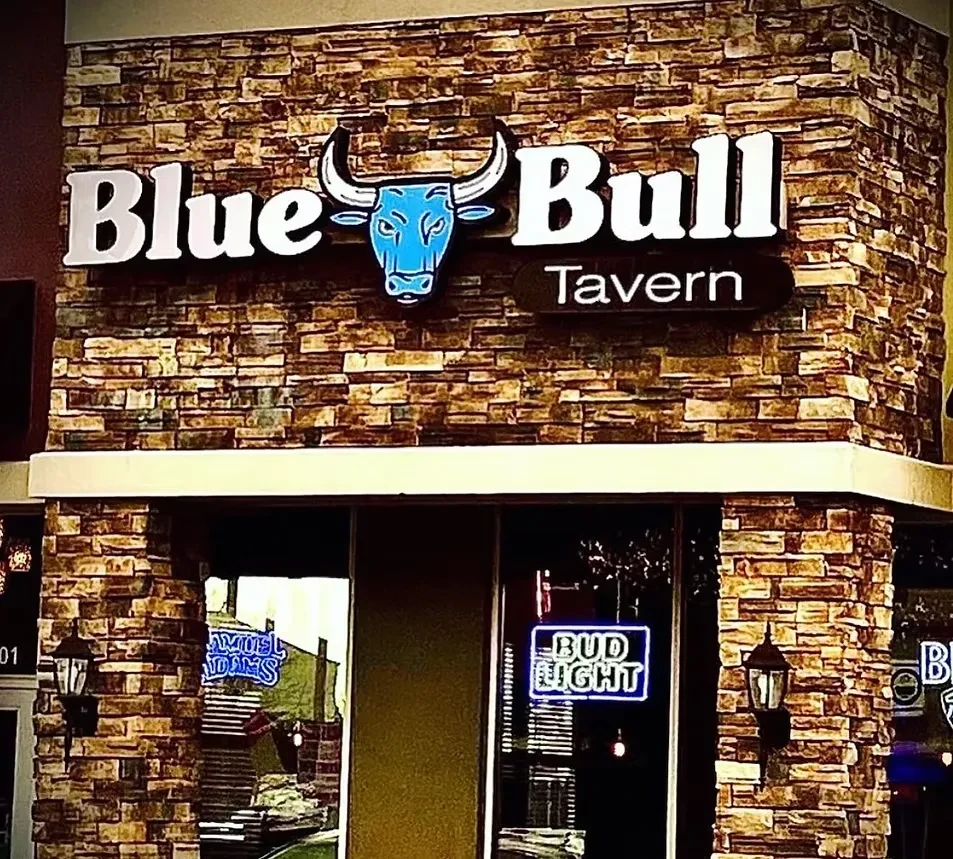 Blue Bull Tavern exterior with stacked stone facade and illuminated signs.