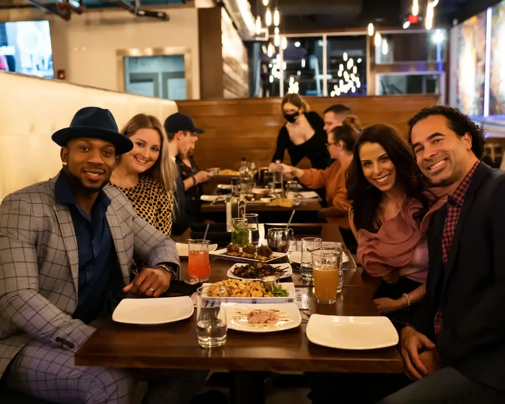Two couples smile directly at camera in a lively modern restaurant.