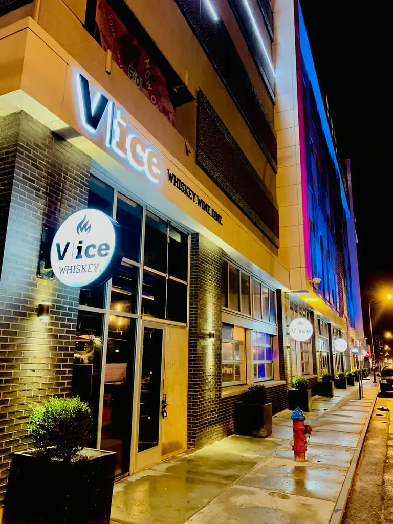 Illuminated "Vice" exterior at night with brick facade and wet sidewalk.