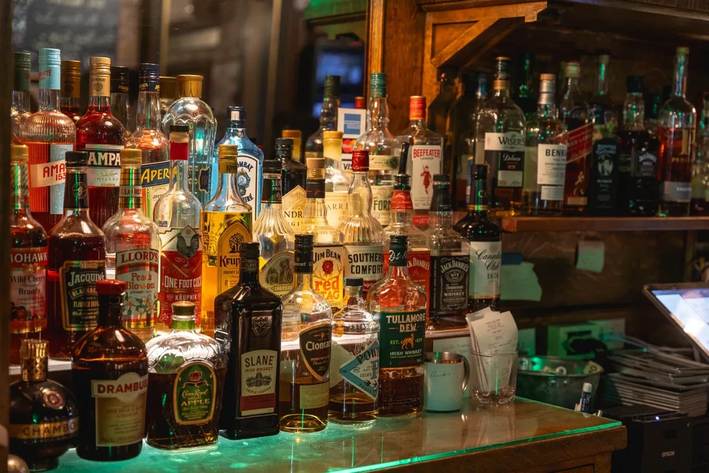 A diverse array of liquor bottles on a glowing bar counter.