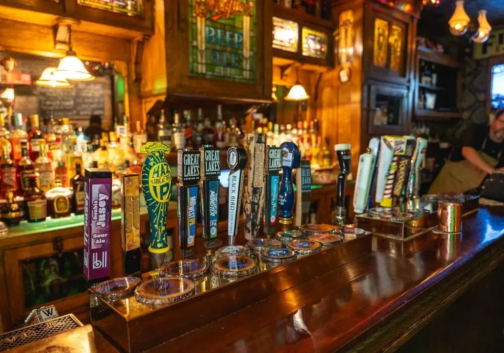 Long wooden bar counter with numerous beer taps and liquor bottles.