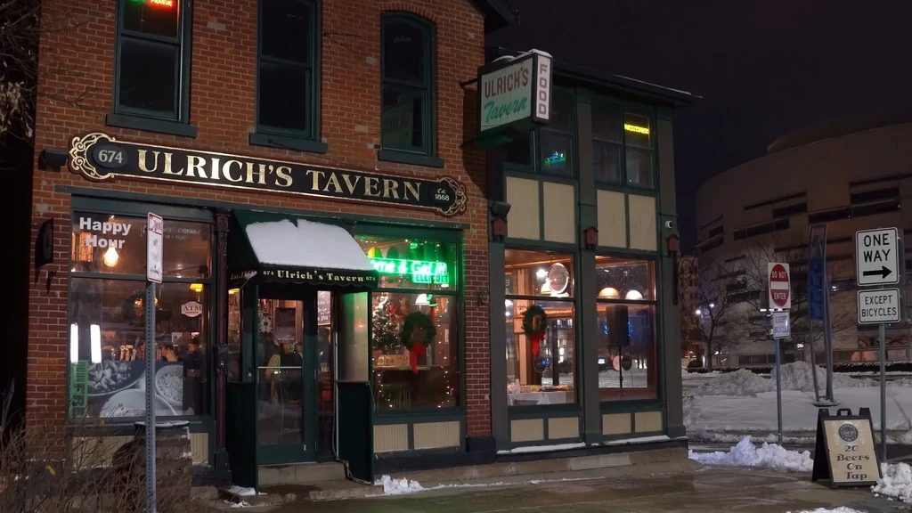 Snow-covered Ulrich's Tavern, a historic brick building glowing at night.