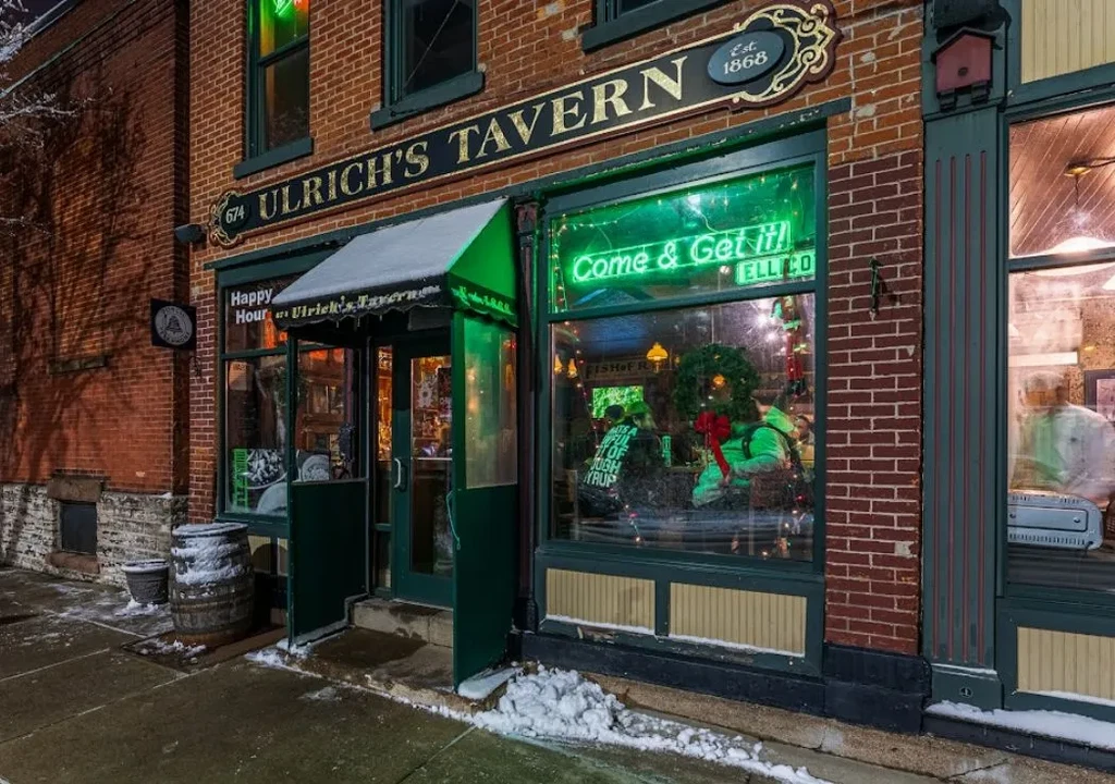 Historic Ulrich's Tavern at night, snowy brick exterior, warm glow.