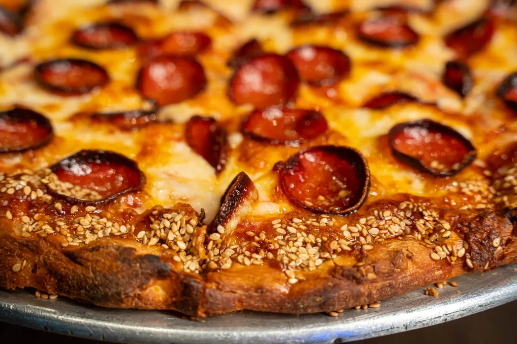 Pepperoni pizza with sesame crust, melted cheese, and curled pepperoni.